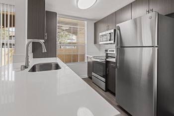 A kitchen with stainless steel appliances and white counter tops