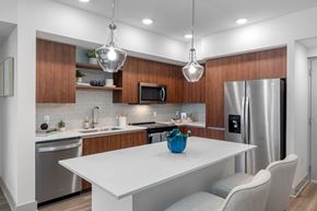 Miramar apartment for rent - A modern kitchen with a white table and wooden cabinets.
