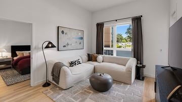 Torrance apartment for rent - A living room with a white couch, a grey ottoman, and a painting on the wall.
