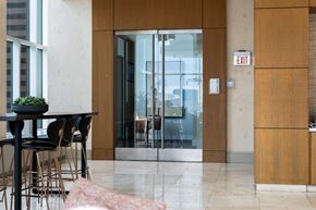 Los Angeles apartment for rent - A modern dining area with a table and chairs, a glass door, and a white exit sign on the wall.