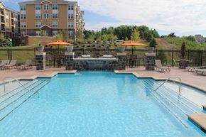 Woodbridge apartment for rent - a swimming pool with chairs and umbrellas in front of an apartment building