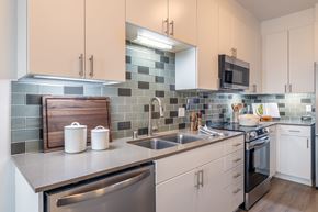 Seattle apartment for rent - A kitchen with white cabinets and a stainless steel dishwasher.