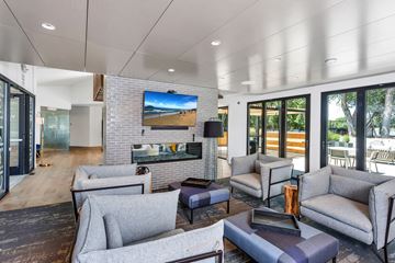 Denver apartment for rent - A modern living room with grey couches and a flat screen TV mounted on the wall.
