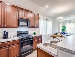 Conroe apartment for rent - a kitchen with wooden cabinets and stainless steel appliances at The Village at Caney Mills, Conroe, TX, 77303