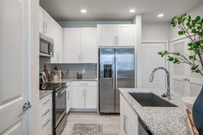 Houston apartment for rent - a kitchen with white cabinets and a stainless steel refrigerator