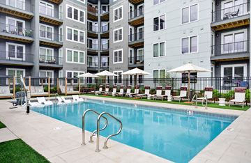 Abington apartment for rent - A swimming pool surrounded by lounge chairs and umbrellas in front of apartment buildings.