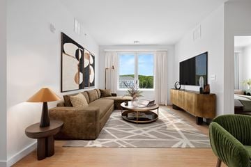 North Attleborough apartment for rent - A living room with a brown couch, a green armchair, a coffee table, and a painting on the wall.