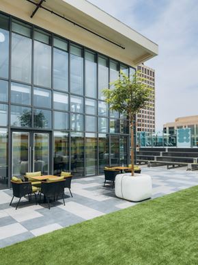 Glendale apartment for rent - A modern building with a glass facade and a small outdoor seating area.