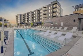 Lehi apartment for rent - A swimming pool with lounge chairs and apartment buildings in the background.