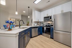 Charlotte apartment for rent - Luxury Apartments in Charlotte NC - The Banks at Rivergate - a kitchen featuring stainless steel appliances, a counter, and blue lower cabinetry