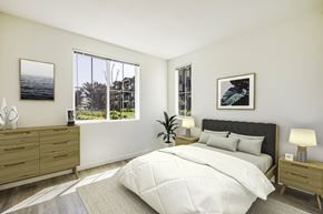 Brentwood apartment for rent - A bedroom with a large bed, a nightstand, and a window with a view of a tree and a building outside.