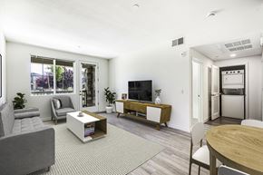 Brentwood apartment for rent - A living room with a grey couch, a white coffee table, a television, and a dining table.
