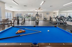 Casa Grande apartment for rent - A pool table with a pool ball and cue sticks in the foreground and a gym in the background.