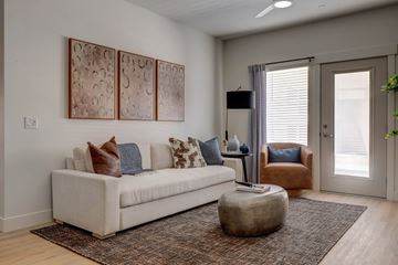 Farmington apartment for rent - A living room with a white couch and a brown ottoman.