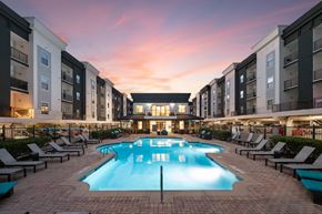 Chamblee apartment for rent - A large swimming pool surrounded by lounge chairs in front of apartment buildings.