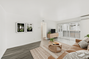 San Jose apartment for rent - A living room with a brown couch, a coffee table, and two framed pictures on the wall.