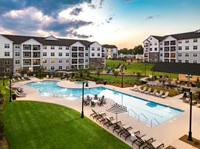 Chattanooga apartment for rent - A large outdoor swimming pool surrounded by lounge chairs and umbrellas.