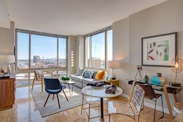 New York apartment for rent - A living room with a couch, chairs, and a table with a view of the city.