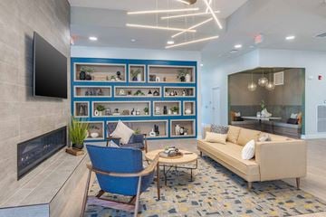 Rochester apartment for rent - A modern living room with a blue chair and a fireplace.