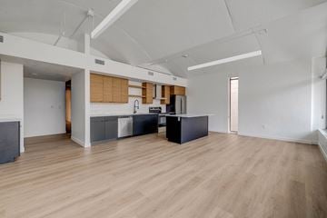 Salt Lake City apartment for rent - A spacious room with wooden floors and a kitchen area with a sink and stove.