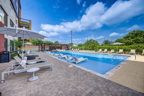 Austin apartment for rent - A large outdoor swimming pool with sun loungers and umbrellas.