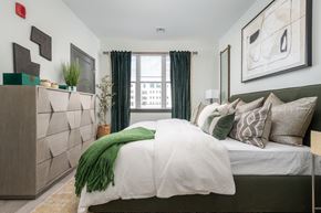 Ronkonkoma apartment for rent - A bedroom with a large bed and a green throw blanket.