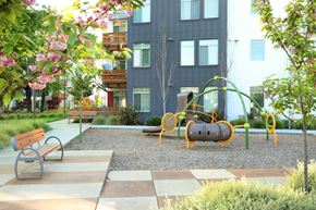 Santa Rosa apartment for rent - A playground with a slide, swings, and a bench in front of a building.