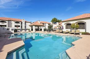 Mesa apartment for rent - A large swimming pool in front of a building with a clear blue sky above.