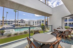 Phoenix apartment for rent - A patio with a table and chairs overlooks a pool and a building.