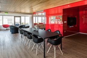 San Francisco apartment for rent - a room with a long black table with black chairs and a red wall with a television in
