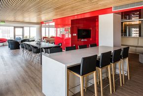 San Francisco apartment for rent - Studios in San Francisco CA - Trinity Place at 33 8th - Clubhouse Lounge Space with Red Accent Walls, TV, Couches, Tables with Chair, and City Views Through Large Windows
