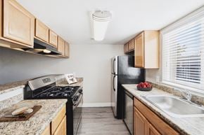 Santa Rosa apartment for rent - A kitchen with a black refrigerator, a stove, and a counter with a cutting board on it.