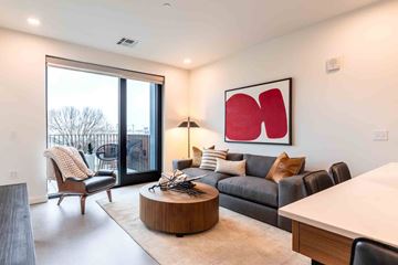Tulsa apartment for rent - A modern living room with a large window and a red abstract painting on the wall.