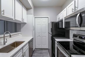 Kansas City apartment for rent - a kitchen with white cabinets and black appliances