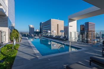 Resort-style pool deck with daybeds and panoramic skyline views