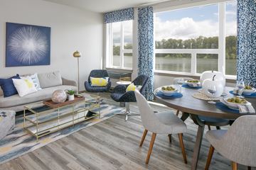 Portland apartment for rent - A modern living room with a grey sofa, a coffee table, and a dining table set for a meal.