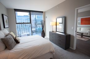 Chicago apartment for rent - A bedroom with a large bed and a city view through the window.