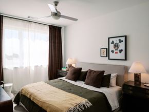 Denver apartment for rent - A bedroom with a bed, two lamps, a ceiling fan, and two pictures on the wall.