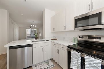 San Diego apartment for rent - A modern kitchen with white cabinets and stainless steel appliances.