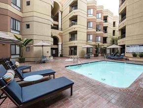 Long Beach apartment for rent - A pool surrounded by chairs and umbrellas in a courtyard.