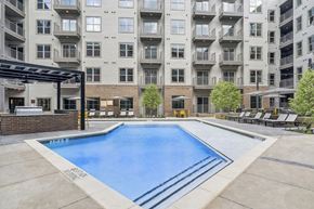 Dallas apartment for rent - A large swimming pool in front of a multi-story apartment building.