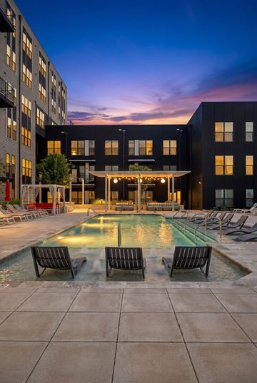 Charlotte apartment for rent - A pool surrounded by chairs and buildings at dusk.