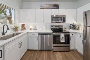 Tempe apartment for rent - A modern kitchen with white cabinets and stainless steel appliances.