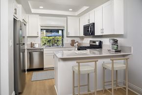 Ontario apartment for rent - A kitchen with white cabinets and a black fridge.