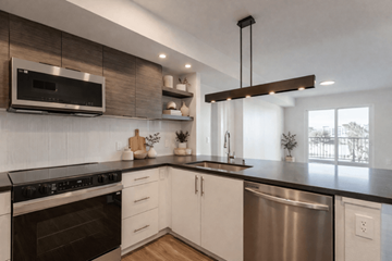 San Diego apartment for rent - A modern kitchen with a stainless steel dishwasher and black countertops.