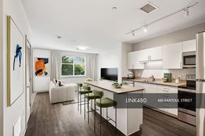 Beverly apartment for rent - A modern kitchen with white cabinets and a dining area with a white sofa and chairs.