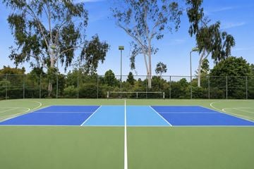 Vista apartment for rent - A tennis court with a blue top and green bottom is surrounded by trees.