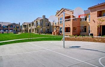 A basketball court is located in front of a row of houses.