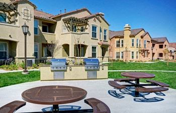 A sunny day at a residential area with a picnic table and a grill.