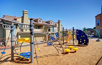 A playground with a yellow slide and blue and yellow swings.